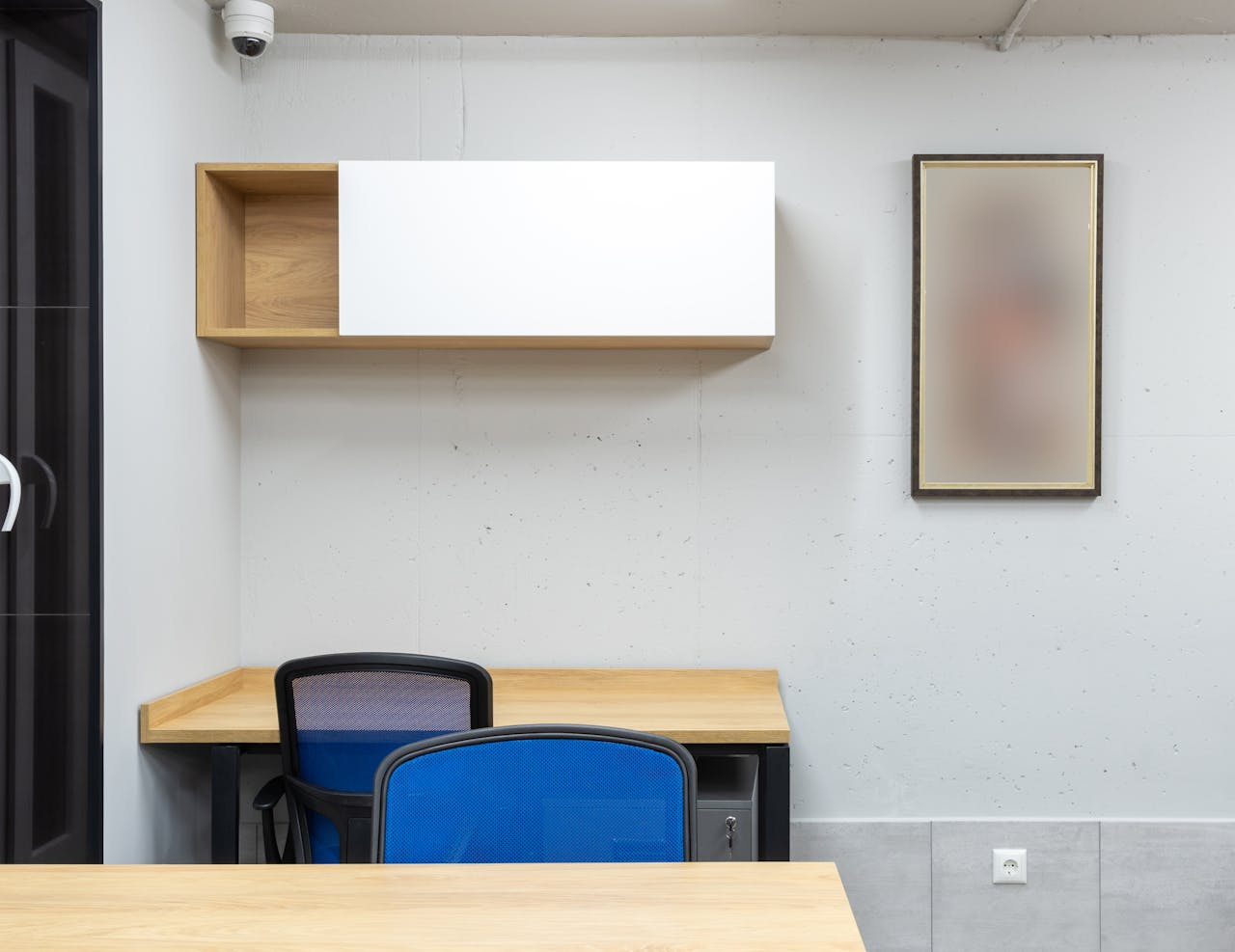 our-story-01 Wooden tables and blue office chairs placed in modern workplace with shelves on wall